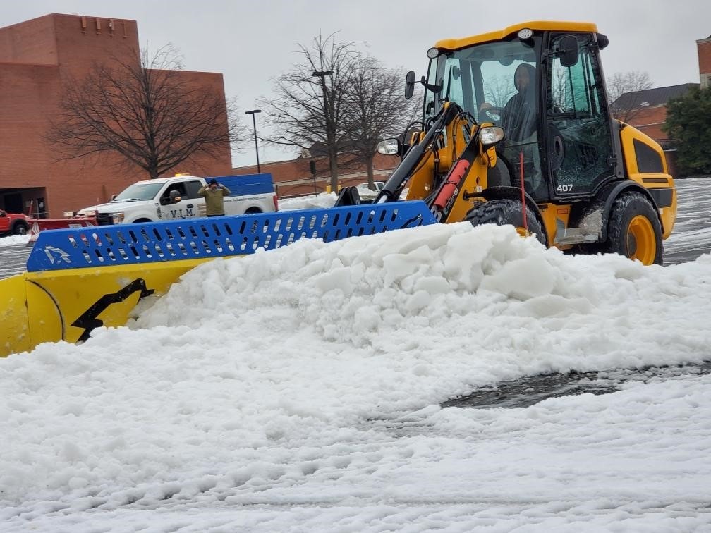 JCB loader pushing snow — commercial parking lot